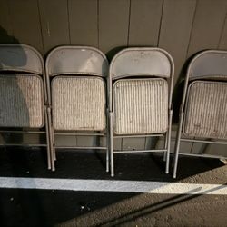 Four metal folding chairs with upholstered seats.