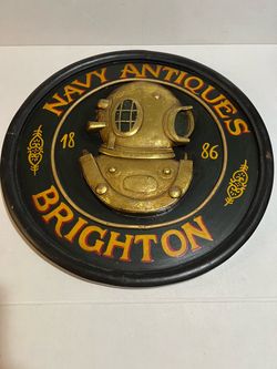 vintage decorative round wall plaque featuring a 3D-relief deep-sea diving helmet with the text "NAVY ANTIQUES BRIGHTON