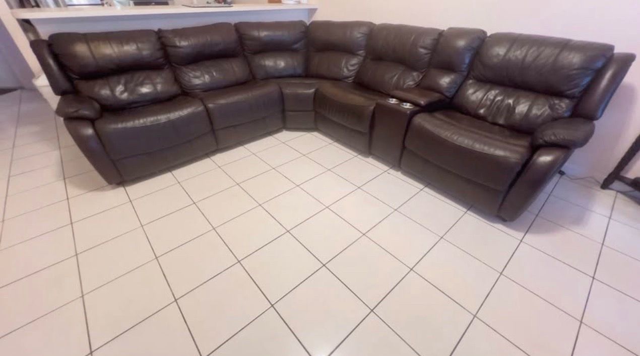 Moon-shaped sofa in dark brown. It has a built-in charger so you can charge your phone or whatevery