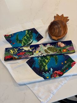 Hawaiian decor including hanging tile art, dish towel, and wooden coconut catch all