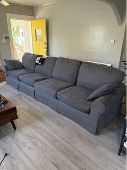 Large four seat slip covered grey sofa