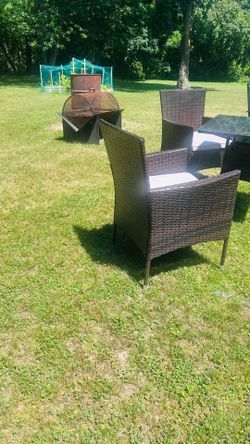 Resin wicker patio set with two chairs, cushions, and glass top