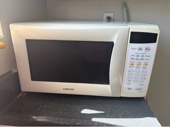 White Samsung MW1245WB microwave has a glass turntable and a digital control panel.