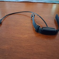 Black Fitbit Inspire 2 fitness tracker and its charger. 
