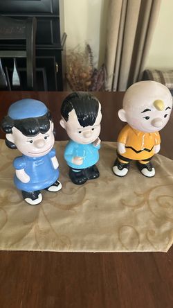 three vintage, hand-painted ceramic figurines of Peanuts characters—Lucy, Linus, and Charlie Brown. These appear to be hobbyist or mold-cast ceramic p