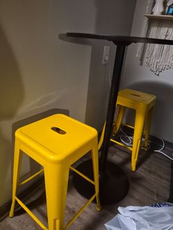 Two yellow barstools and black round table