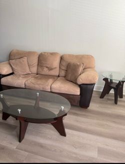 Brown and coffee-colored sofa for sale, along with three wooden tables with glass tops.