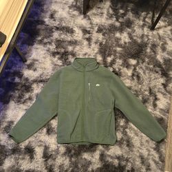 This is a Nike Club Winter Jacket in the green (Fir/White) colorway and high-pile fleece material. 