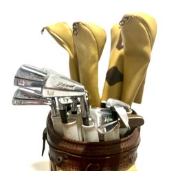vintage golf club set featuring a brown leather-style bag and several clubs with yellow headcovers. 