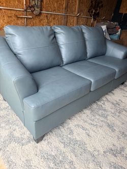 Ashley Genoa Steel sofa features a gray leather match finish and flared arms.