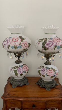 pair of vintage milk glass hurricane lamps with hand-painted roses and crystal prisms.