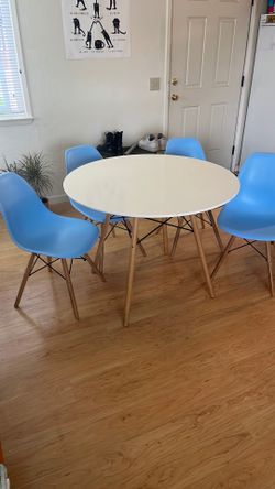 White table with blue chairs and wooden legs