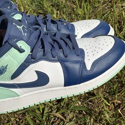 Nike Air Jordan 1 Mid sneakers, specifically in a colorway that blends shades of blue, white, and a mint green accent.
