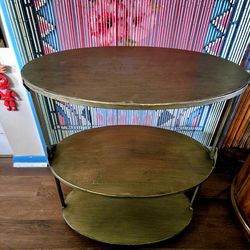 antique gold oval metal shelf or side table. It features a sleek metal frame with a shiny finish and three oval tiers 30"×24"×14"
