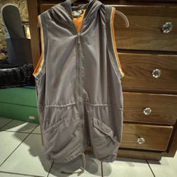Grey sleeveless hooded vest with orange interior lining and striped arm cuffs