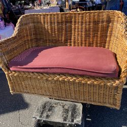 vintage rattan loveseat or settee with a red cushion
