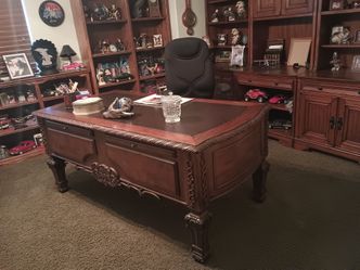 An executive desk very large and cabinets behind it and one chair