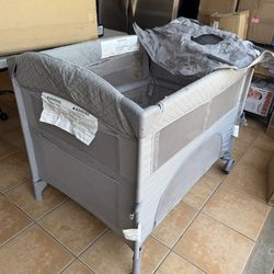 Folding Bedside Bassinet and Play Yard Featuring Breathable Mesh Sides with Side Pockets for Storage