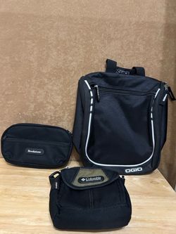 three black travel and utility bags, featuring an OGIO Doppler Toiletry Kit on the right, a Brookstone zippered pouch on the left, and a Columbia Spor