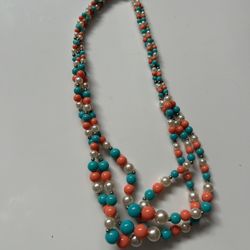multi-strand beaded necklace featuring faux pearls, and beads colored to resemble coral and turquoise