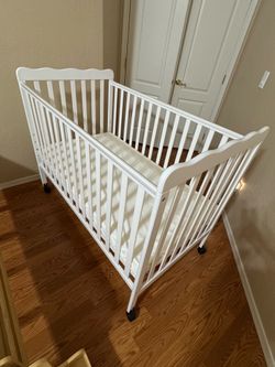 White crib and mattress due side