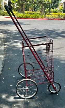 Sturdy red metal shopping cart with large wheels.