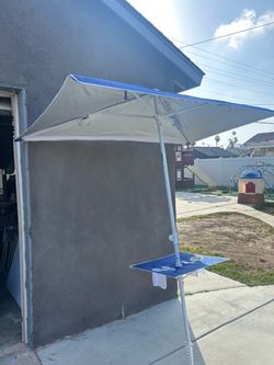 Blue and white beach umbrella with table and cup holders