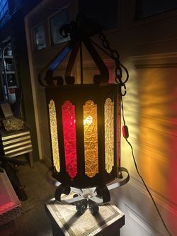 Very large and vintage wrought iron chandelier with hanging chain and switch in excellent condition. Has three colors of glass with no chips, brakes o