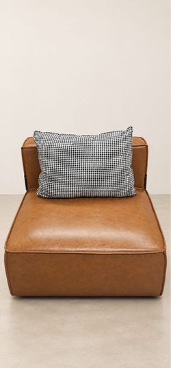 Caramel brown accent chair with a leather-look finish and a black-and-white houndstooth pillow included.