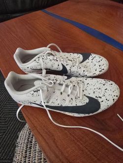 Men's Nike athletic shoes with bold black swoosh. White upper features black splatter pattern. Lace-up closure for a snug fit. Low-profile design for 