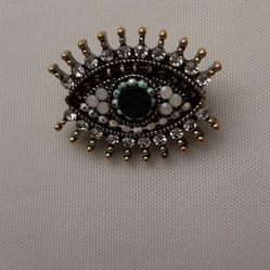 Decorative eye-shaped brooch with gemstones.
