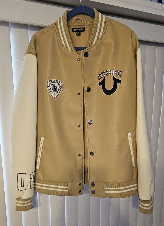 True Religion varsity jacket in tan and Cream . Features bold logo patches and button-up front. Unisex.