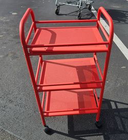 Red IKEA DRAGGAN 3-tier trolley features mesh shelving and casters for easy mobility.