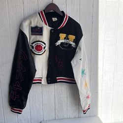 una chaqueta universitaria recortada de estilo Y2K con parches bordados y bloques de color, comúnmente comercializada por marcas como JJdocvanatic. C