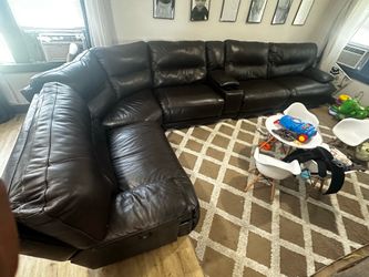 “Brown leather reclining sectional with cup holder console”