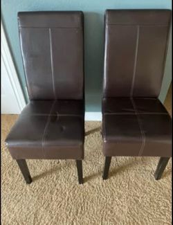 Two brown faux leather dining chairs