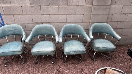  is a set of vintage mid-century modern chrome swivel dining chairs with blue naugahyde upholstery.