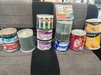 assortment of multiple multi-pack spindles and jewel cases containing blank recordable optical media, including various brands of CD-R, DVD-R, and DVD