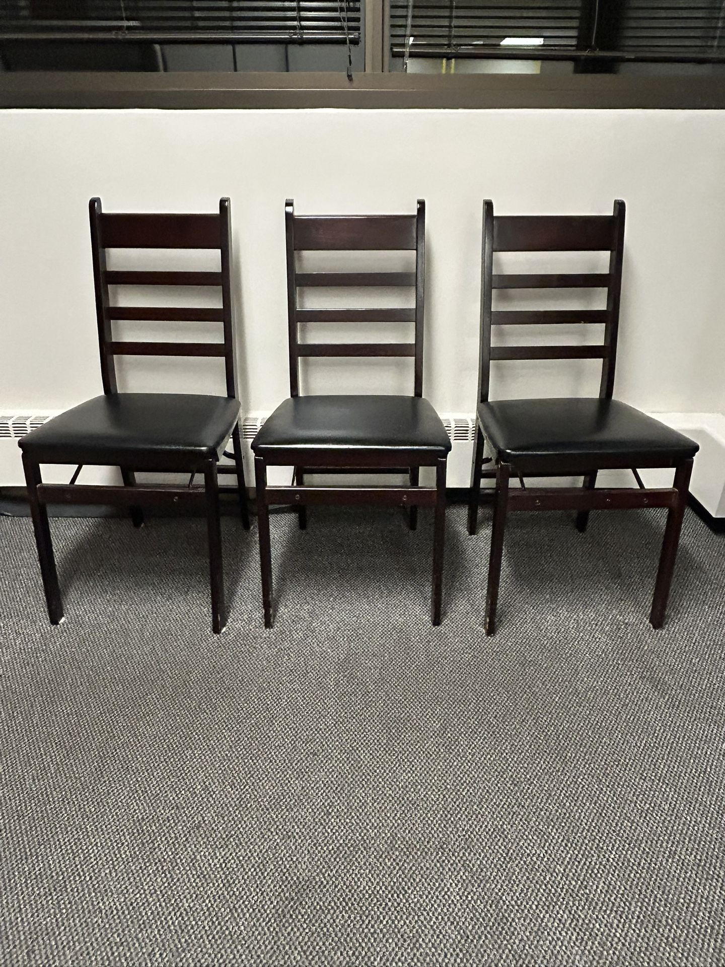Six wooden chairs with black cushioned seats