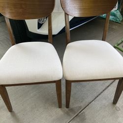 Two wood chairs with off-white cushions