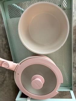 Pink Redchef ceramic cookware set has two pots, one pan, two glass lids, and one detachable handle. The cookware has a cream-colored ceramic non-stick