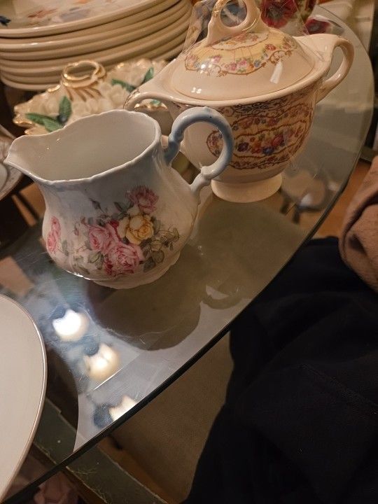 The items are porcelain or bone china teaware, specifically a creamer or milk jug with a floral design