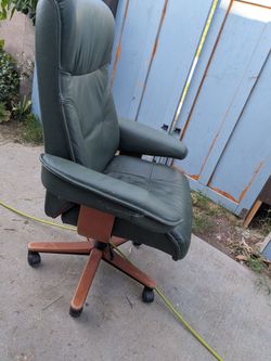 Green leather roller chair reclines some pen writing on backrest part