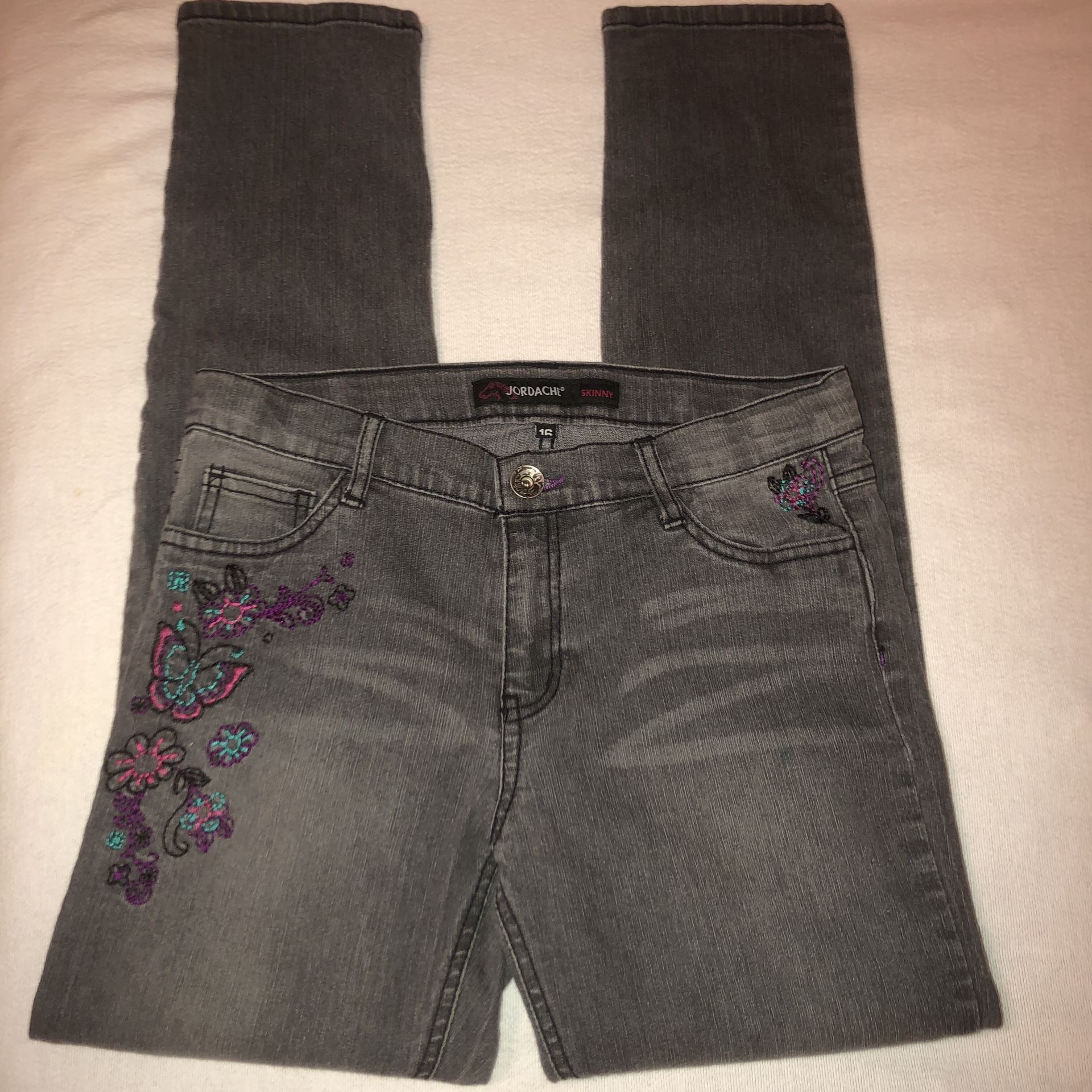 Kids Jordache size 16 faded black/grey skinny jeans with floral embroidery on the front. There’s a small spot on the leg I believe is just from layin