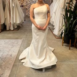 Romona Keveza Strapless gown made of silk crepe, features an asymmetrical neckline and a fluted skirt. 