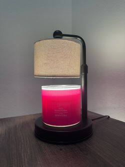Español: Lámpara de mesa negra con pantalla beige y vela decorativa. English: Black Table Lamp with Beige Shade and Decorative Candle.