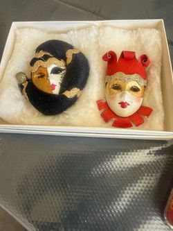 a pair of small, decorative Venetian-style jester and carnival face masks