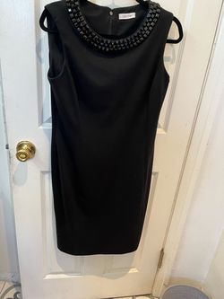 Calvin Klein is a designer on this black dress with beads around the neck line