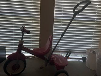 Red Radio Flyer tricycle with push handle.
