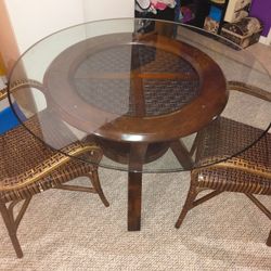 Glass Dining Room Table With Oak Wood Bottom And Two Brown Rattan Bamboo Style Armchairs 